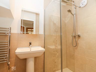 A bathroom with a pedestal sink mirror towel rail and a glass door shower at Ty Top in Llanfaethlu