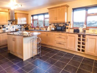 A kitchen with wooden cabinets a center island and tiled floor at Tynddol Bungalow Llanbadarn-Fynydd near Llanbister