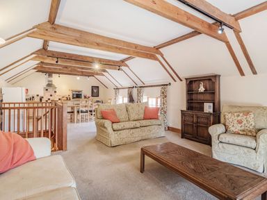 A living room with sofas wooden beams and a table at Punch Cottage in Little Glemham near Wickham Market