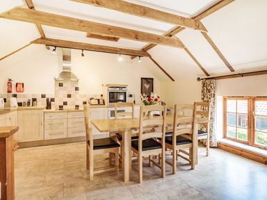 A kitchen and dining area with wooden table and chairs and a window at Punch Cottage in Little Glemham near Wickham Market