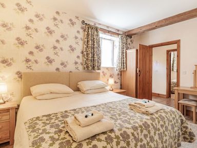 A bedroom with a large bed and floral patterned bedspread at Punch Cottage Little Glemham near Wickham Market