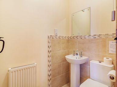 A bathroom with a pedestal sink mirror toilet paper holder and radiator at Punch Cottage in Little Glemham near Wickham Market