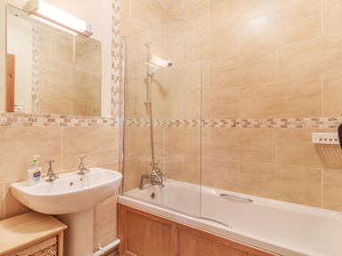 A bathroom with a sink and a bathtub with shower screen at Punch Cottage in Little Glemham near Wickham Market