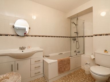 A bathroom with a sink and cabinet a bathtub with a shower and a toilet at 37 Ocean Park in Westward Ho