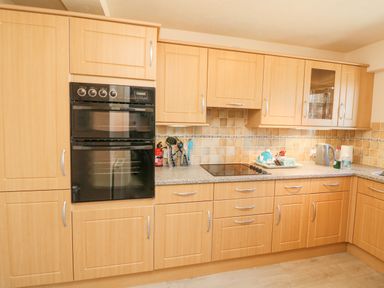 A kitchen with wooden cabinets black double oven electric stovetop and countertop appliances at 37 Ocean Park in Westward Ho