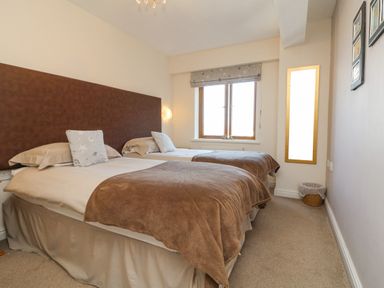 A bedroom with two single beds brown blankets and a window at 37 Ocean Park in Westward Ho