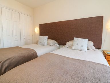A bedroom with two single beds with brown headboard and beige bedding at 37 Ocean Park in Westward Ho
