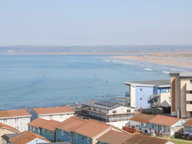 Rooftops of houses and buildings by a beach with the ocean and distant hills at 37 Ocean Park in Westward Ho