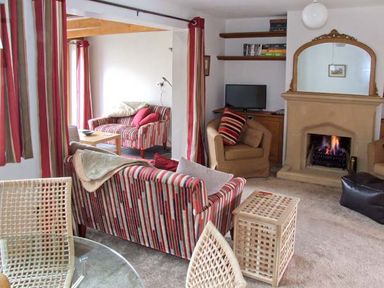 A living room with striped sofas a fireplace shelves and a television at Hour Cottage in Stow on the Wold