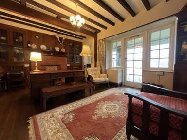 A living room with wooden furniture and a rug at Murmur Y Don in Harlech