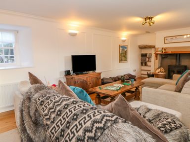 A living room with sofas wooden coffee table television and a fireplace at East Farm House in Humshaugh near Hexham