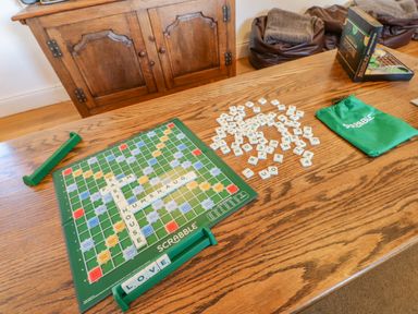 A wooden table with a Scrabble board game with words East Farm House Humshaugh and letter tiles on the table at East Farm House in Humshaugh near Hexham