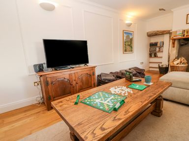 A living room with a wooden coffee table set up for a board game and a television on a wooden cabinet at East Farm House Humshaugh near Hexham