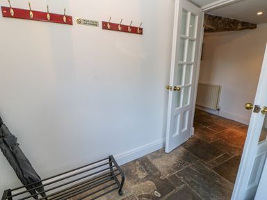 A hallway with an umbrella stand a wall-mounted coat rack with hooks and a glass-paneled door at East Farm House Humshaugh near Hexham
