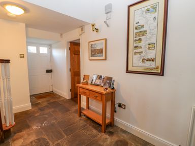An entryway with a wooden door a small wooden table a map on the wall and tiled flooring at East Farm House Humshaugh near Hexham