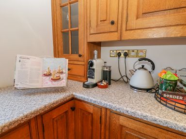 A kitchen corner with wooden cabinets a coffee machine a kettle and a recipe book at East Farm House in Humshaugh near Hexham