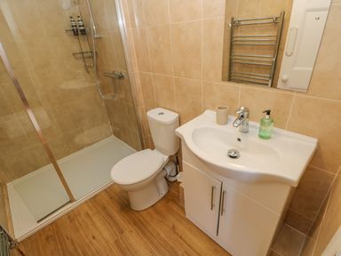 A bathroom with a shower with glass door a toilet and a sink with soap dispenser at East Farm House in Humshaugh near Hexham
