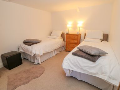 A bedroom with two single beds a wooden chest of drawers two lamps and a small rug at East Farm House in Humshaugh near Hexham