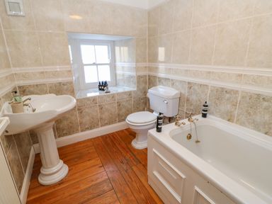 A bathroom with a pedestal sink a toilet a bathtub and a window at East Farm House Humshaugh near Hexham
