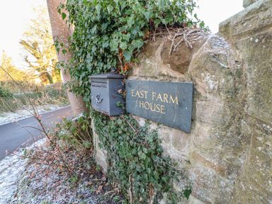 A stone wall with a mailbox and a sign that reads East Farm House covered with ivy at East Farm House Humshaugh near Hexham
