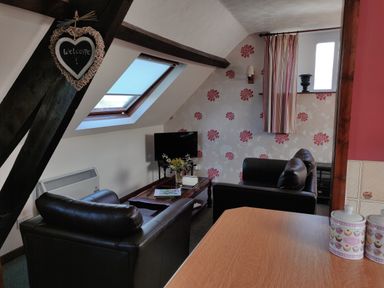 A sitting area with two black armchairs a coffee table a television and floral wallpaper at The Coach House in North Newton near Bridgwater
