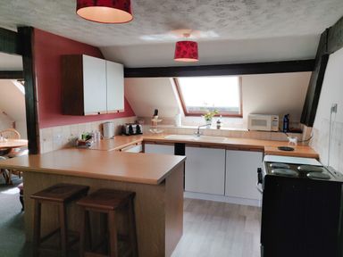 A kitchen with wooden countertops a sink a microwave and two stools at The Coach House in North Newton near Bridgwater