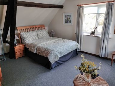 A bedroom with a double bed bedside tables a window and a small table with flowers at The Coach House in North Newton near Bridgwater