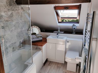 A bathroom with bathtub shower sink toilet and open skylight window at The Coach House in North Newton near Bridgwater