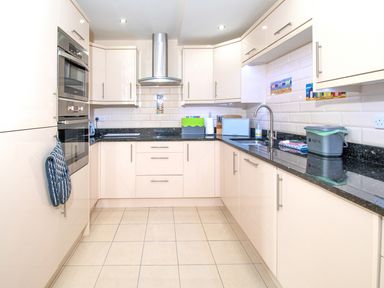 A kitchen with cream cabinets black countertops tiled floor and built in oven at The Moorings in Deganwy near Llandudno