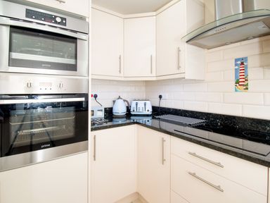 A kitchen corner with built in double oven trolley units a kettle toaster and electric stove with extractor hood at The Moorings in Deganwy near Llandudno