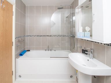 A bathroom with a bathtub shower sink and mirror cabinet at The Moorings in Deganwy near Llandudno