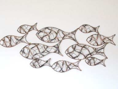 Metal wall art sculpture of multiple abstract fish shapes on a white wall at The Moorings in Deganwy near Llandudno