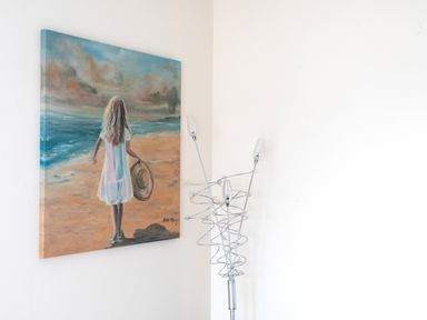 A painting of a girl holding a hat and looking at the ocean on a wall near a modern metal floor lamp at The Moorings in Deganwy near Llandudno