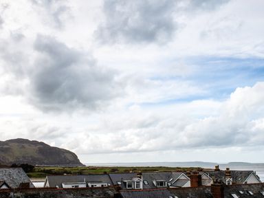Rooftops of houses with a hill and coastline in the background at The Moorings in Deganwy near Llandudno
