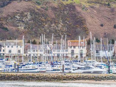 A marina with sailboats and yachts docked in front of houses and hills at The Moorings in Deganwy near Llandudno