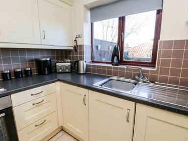 A kitchen corner with a sink toaster kettle and storage containers on the counter at Sunnybrae in Whitby