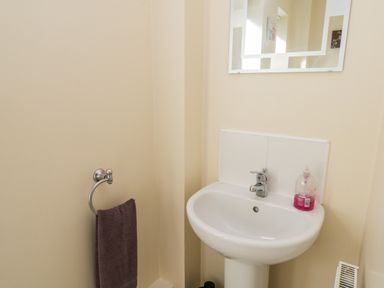 A sink with a mirror above it a towel hanging on a ring and a bottle of soap on the sink at Sunnybrae in Whitby