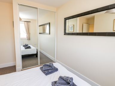A bedroom with a bed with folded towels on it a wall mirror and mirrored wardrobe doors at Sunnybrae in Whitby
