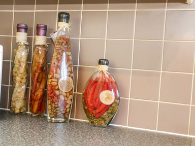 Four glass bottles filled with various pickled vegetables on a kitchen countertop with tiled backsplash at Sunnybrae in Whitby