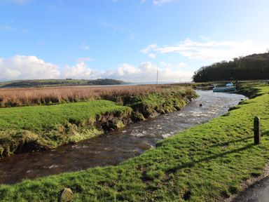 A river flowing through grasslands with a boat moored on the right side at Bwthyn-y-Rhiw in Penybanc near Llandeilo