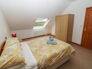 A bedroom with a bed and a wardrobe at Bwthyn-y-Rhiw in Penybanc near Llandeilo