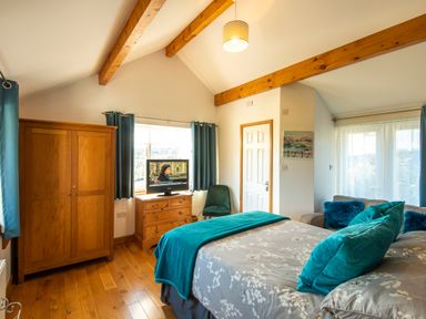 A bedroom with a bed sofa wooden wardrobe chest of drawers and a television at Browside Little Arrow near Coniston
