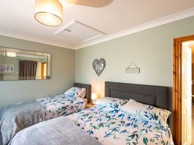 A bedroom with two beds and floral bedding a wall mirror and a heart decoration at Browside Little Arrow near Coniston