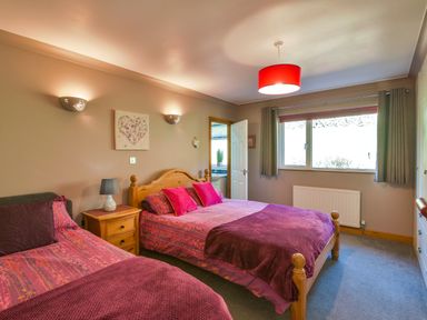 A bedroom with two beds bedside table lamp and a window with curtains at Browside Little Arrow near Coniston