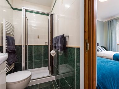 A bathroom with a shower enclosure a toilet towels and a view into a bedroom at Browside Little Arrow near Coniston