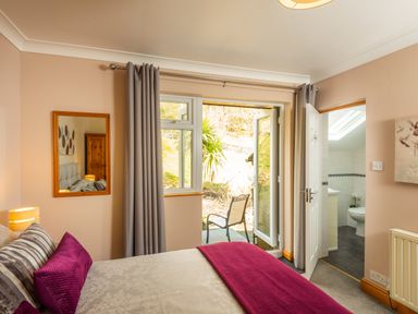 A bedroom with a bed and pillows a mirror on the wall curtains and an open door to a bathroom at Browside Little Arrow near Coniston