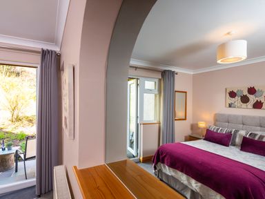 A bedroom with a bed covered in purple and white bedding and an open door to a garden at Browside Little Arrow near Coniston