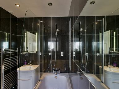 A bathroom with a bathtub shower combination a white sink with cabinet and a towel rack at Browside in Little Arrow near Coniston