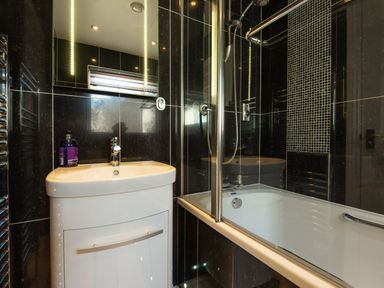 A bathroom with a sink cabinet a mirror bathtub and shower at Browside in Little Arrow near Coniston