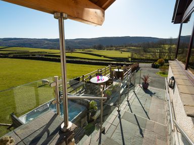 An outdoor patio area with tables and chairs overlooking green fields and hills at Browside Little Arrow near Coniston